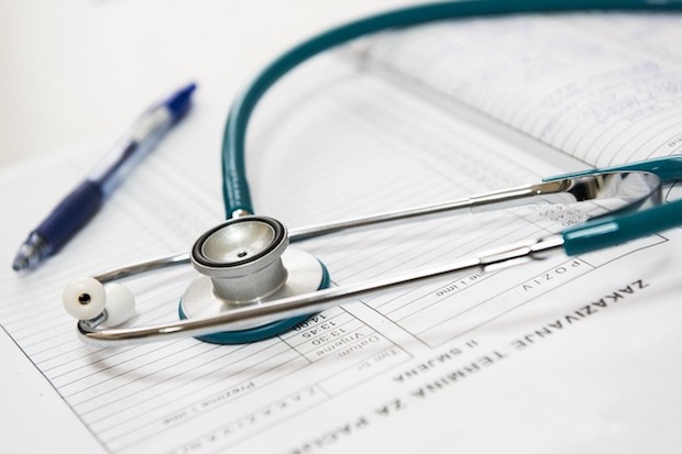 A stethoscope, pen and sheet of patient information