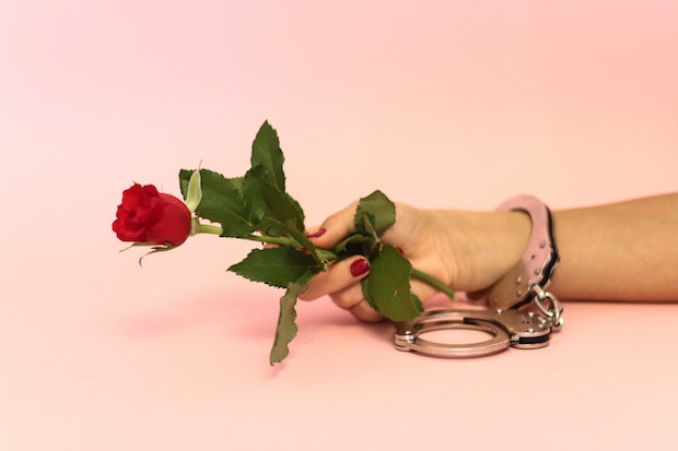 a handcuffed hand holding a rose