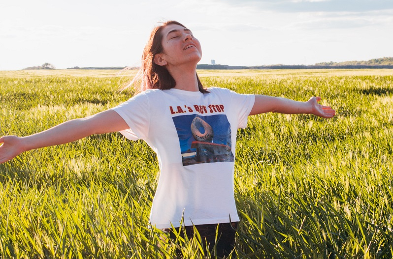 woman in field with arms wide breathing