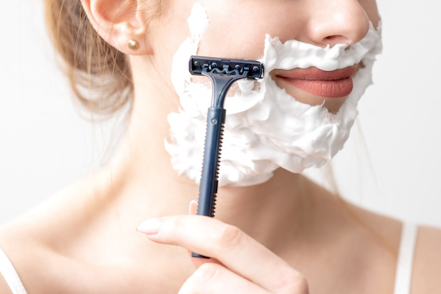 a woman shaving her face