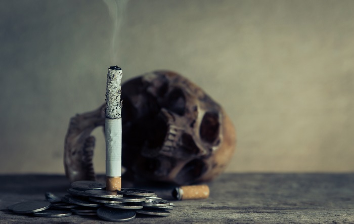 image of burning cigarette with skull in background