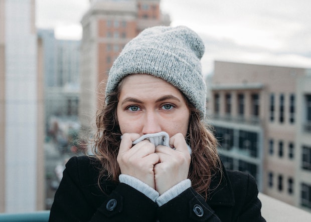 a pale woman covering her face with her sweater