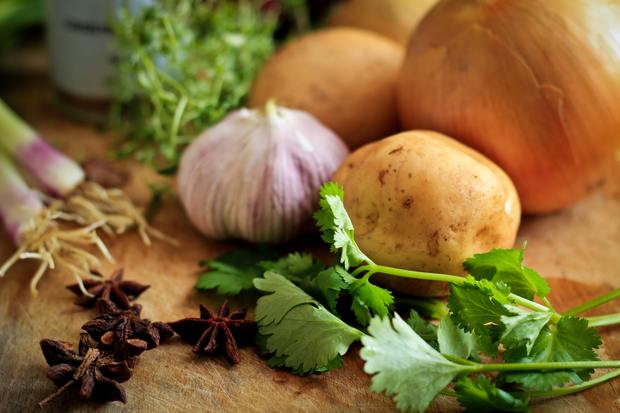 onions, garlic, potatoes, and herbs on a table