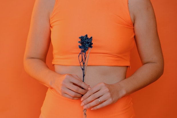 a woman wearing an orange crop top holding lavender